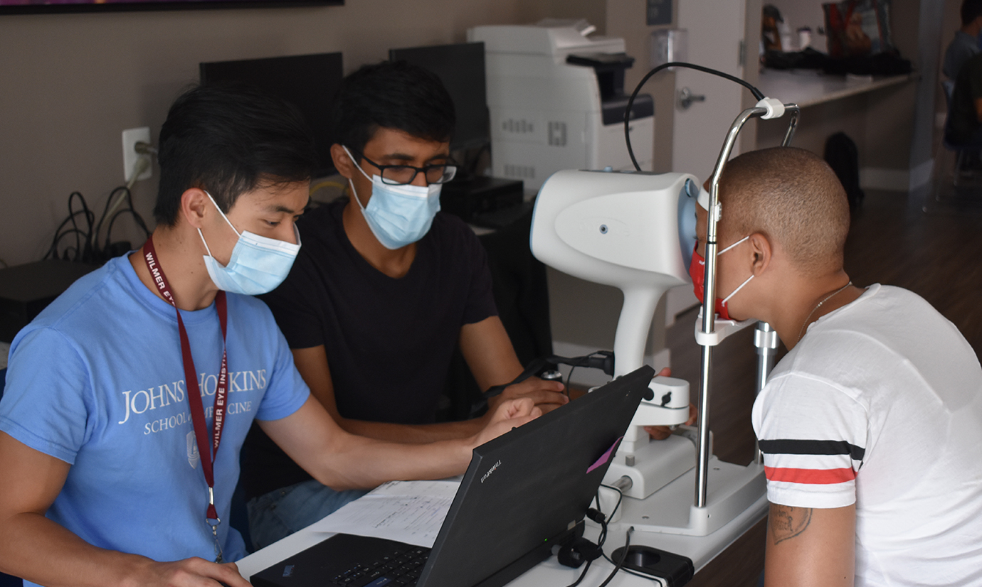 From left, Andrew Nguyen and Siddharth Venkatraman screen a patient at the optical coherence tomography (OCT) station.